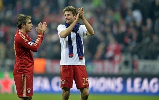 Bayern Munich's Philipp Lahm (L) and Thomas Mueller applaud after the match in Munich on March 13, 2013